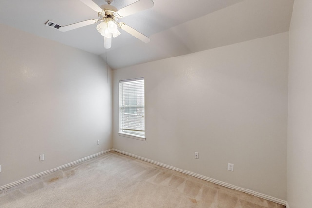 empty room featuring vaulted ceiling, light colored carpet, and ceiling fan