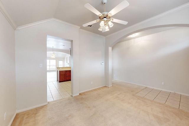 carpeted spare room with vaulted ceiling, ornamental molding, and ceiling fan