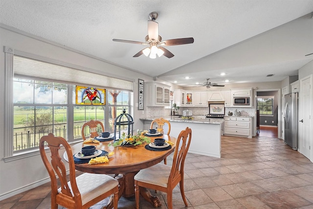 dining space with lofted ceiling, a textured ceiling, and ceiling fan