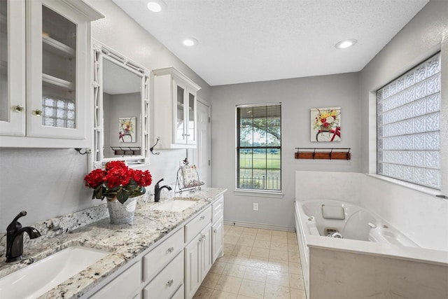 bathroom with vanity, a bathing tub, and a textured ceiling