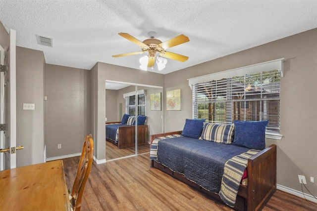 bedroom with hardwood / wood-style floors, a textured ceiling, and a closet