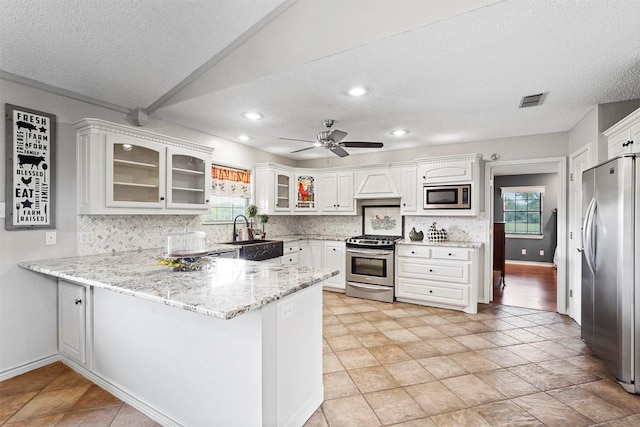 kitchen with appliances with stainless steel finishes, sink, white cabinets, and kitchen peninsula