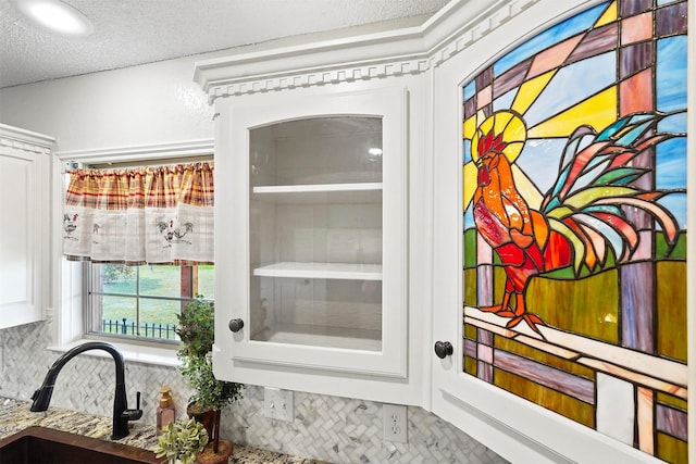 interior details featuring tasteful backsplash, sink, and white cabinets