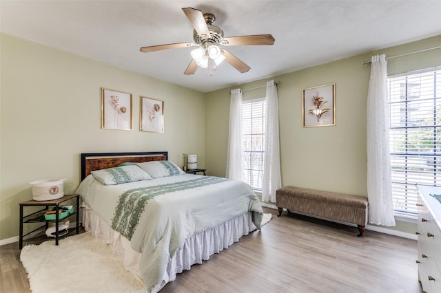 bedroom featuring ceiling fan, light hardwood / wood-style floors, and multiple windows