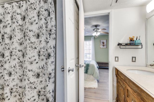 bathroom with hardwood / wood-style floors, curtained shower, vanity, ceiling fan, and a textured ceiling