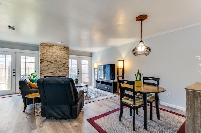 living room featuring hardwood / wood-style flooring, crown molding, a healthy amount of sunlight, and french doors