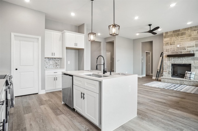 kitchen featuring sink, an island with sink, pendant lighting, stainless steel appliances, and white cabinets