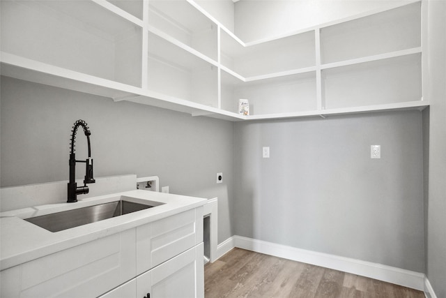 clothes washing area with sink, electric dryer hookup, cabinets, washer hookup, and light hardwood / wood-style floors