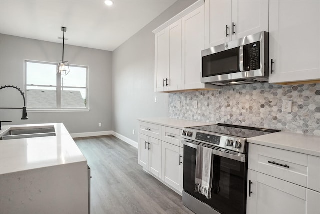 kitchen featuring decorative light fixtures, white cabinetry, sink, decorative backsplash, and stainless steel appliances