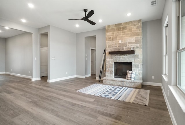 unfurnished living room featuring hardwood / wood-style flooring, ceiling fan, and a fireplace