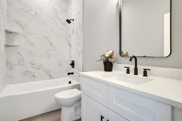 full bathroom with tiled shower / bath combo, vanity, hardwood / wood-style flooring, and toilet