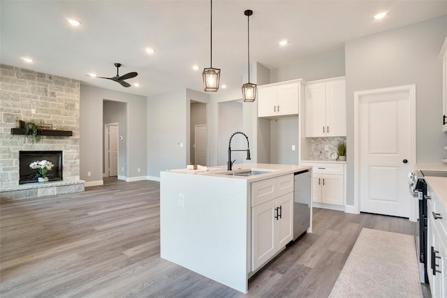 kitchen with white cabinetry, sink, hanging light fixtures, stainless steel appliances, and a center island with sink