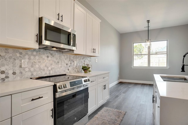 kitchen featuring sink, white cabinets, pendant lighting, stainless steel appliances, and backsplash