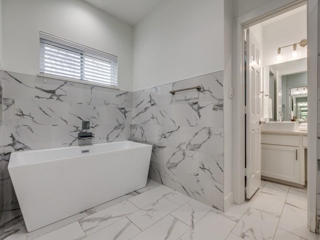 bathroom with vanity, a bath, and tile walls