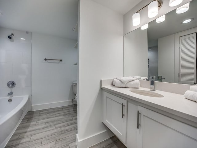 full bathroom with tiled shower / bath, vanity, and toilet