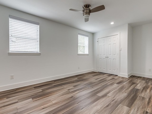 unfurnished bedroom featuring ceiling fan, wood-type flooring, and a closet