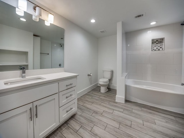 full bathroom featuring vanity, tiled shower / bath, and toilet