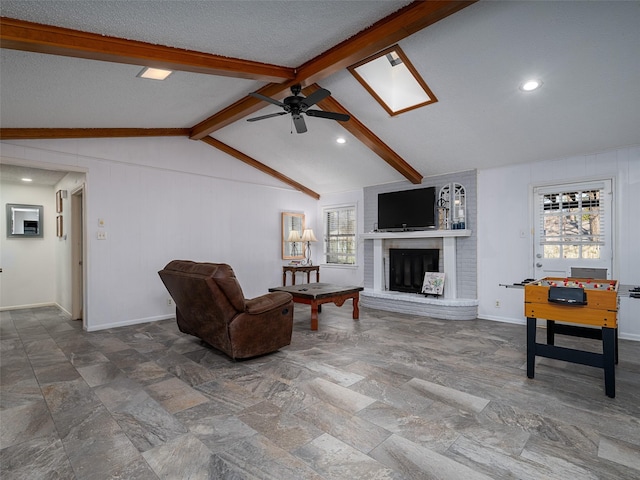 living room featuring ceiling fan, a healthy amount of sunlight, lofted ceiling with skylight, and a brick fireplace