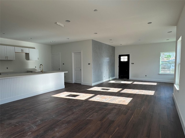 unfurnished living room featuring sink and dark hardwood / wood-style flooring