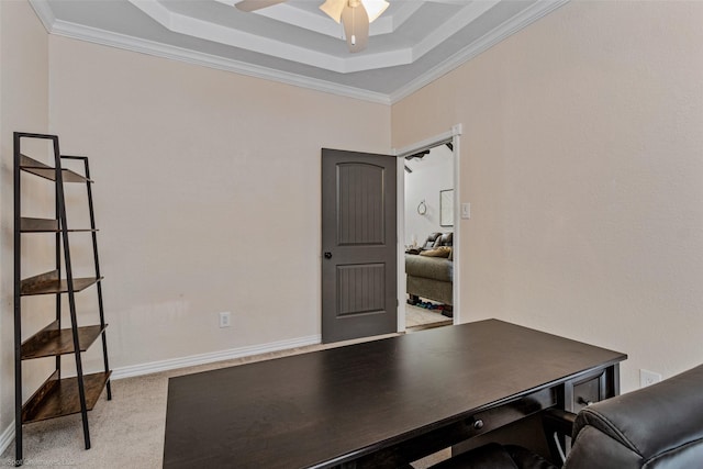 carpeted office space with a tray ceiling, ornamental molding, and ceiling fan