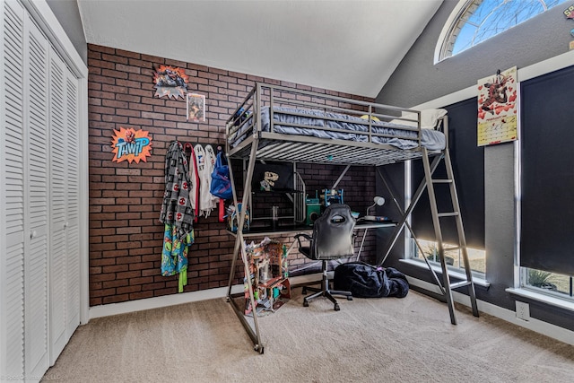 carpeted bedroom featuring vaulted ceiling and brick wall