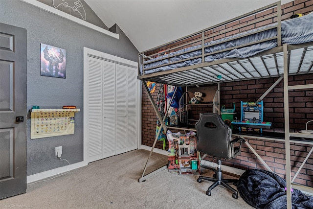 carpeted bedroom with brick wall, lofted ceiling, and a closet