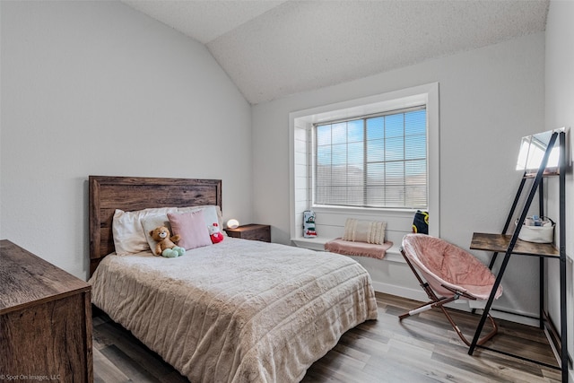 bedroom with lofted ceiling, light hardwood / wood-style flooring, and a textured ceiling