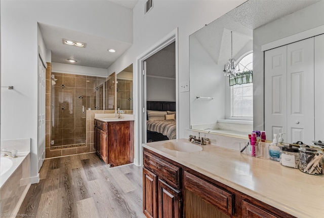 bathroom with hardwood / wood-style flooring, vanity, an inviting chandelier, and plus walk in shower