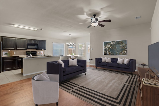 living room featuring sink, ceiling fan with notable chandelier, and light hardwood / wood-style floors