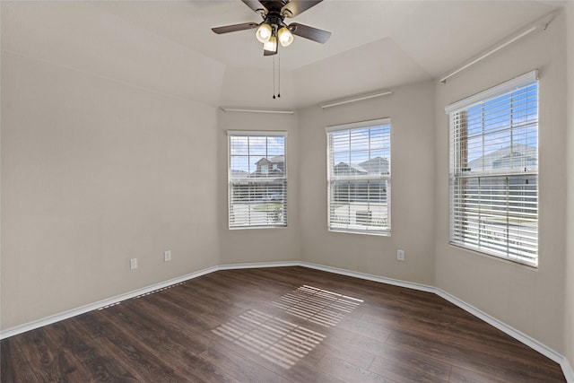 unfurnished room featuring ceiling fan, a tray ceiling, and dark hardwood / wood-style floors