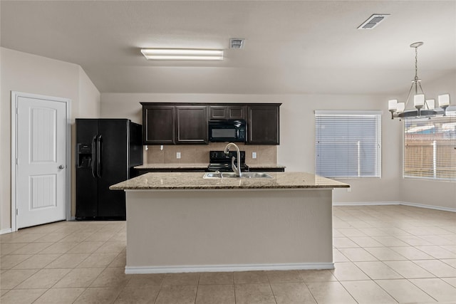 kitchen with sink, a center island with sink, light stone counters, and black appliances