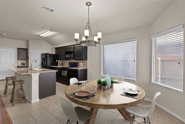 dining room featuring an inviting chandelier, lofted ceiling, sink, and light tile patterned floors