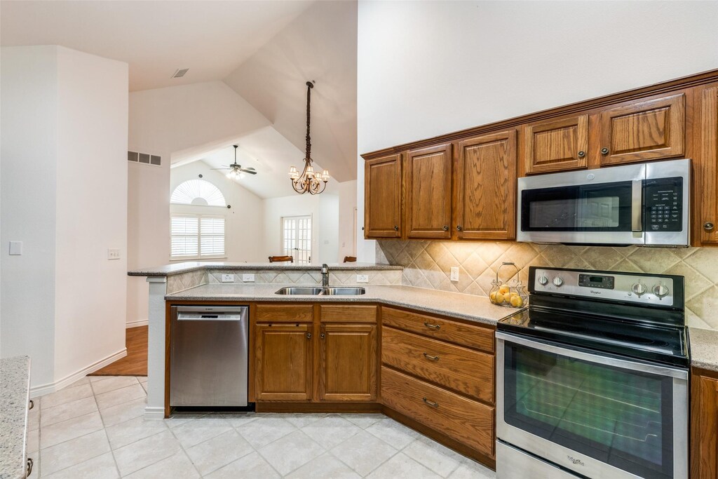 2601 Marsh Ln Unit 193, Plano, TX 75093 - living area featuring ceiling fan with notable chandelier, a high end fireplace, light wood finished floors, lofted ceiling, and visible vents