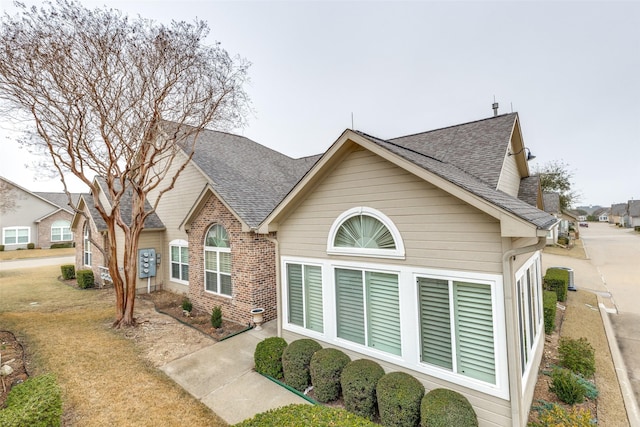 view of front facade featuring brick siding and roof with shingles