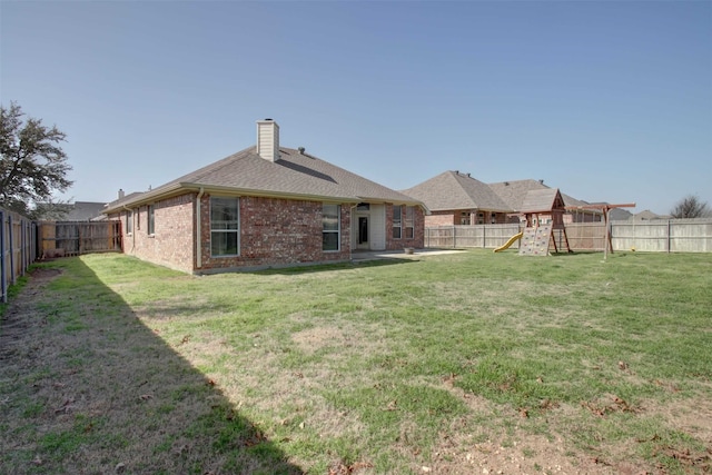 back of property featuring a yard and a playground