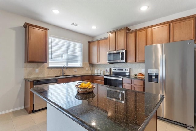 kitchen with stainless steel appliances, tasteful backsplash, a center island, and sink