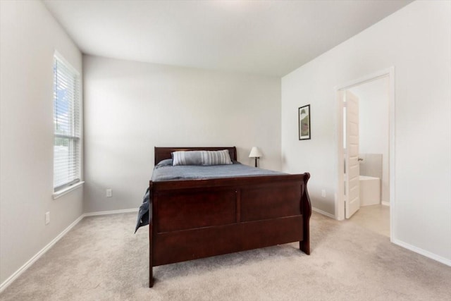 bedroom featuring ensuite bathroom and light carpet