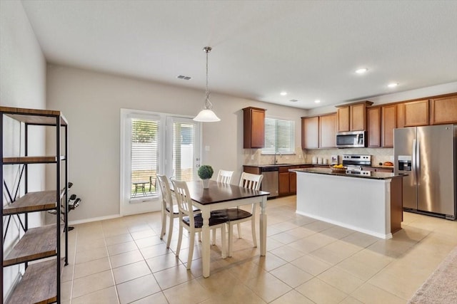 kitchen with sink, light tile patterned floors, appliances with stainless steel finishes, hanging light fixtures, and decorative backsplash