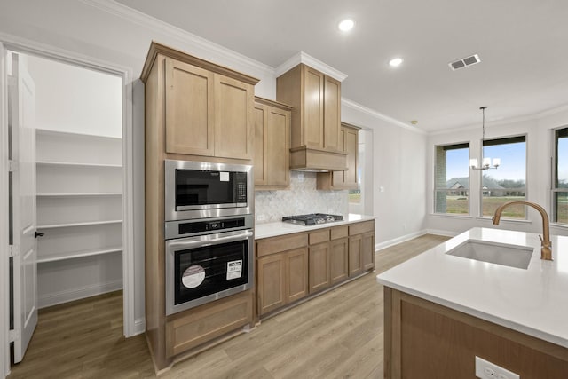 kitchen with stainless steel appliances, a sink, visible vents, and crown molding