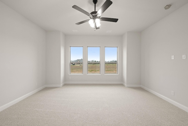 empty room featuring a ceiling fan, light colored carpet, and baseboards