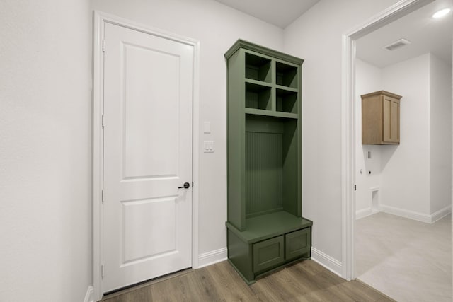 mudroom featuring baseboards, visible vents, and wood finished floors