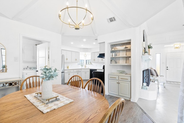 dining room with washer / clothes dryer, vaulted ceiling, and a notable chandelier