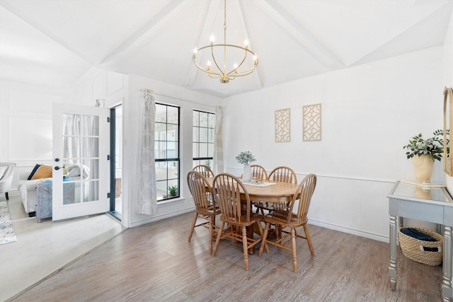 dining room with wood-type flooring, a chandelier, and vaulted ceiling