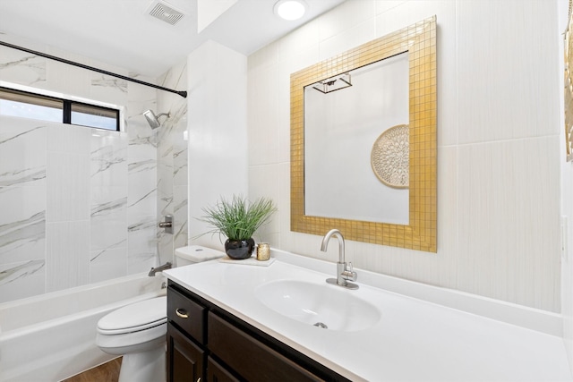 full bathroom featuring tiled shower / bath, vanity, and toilet