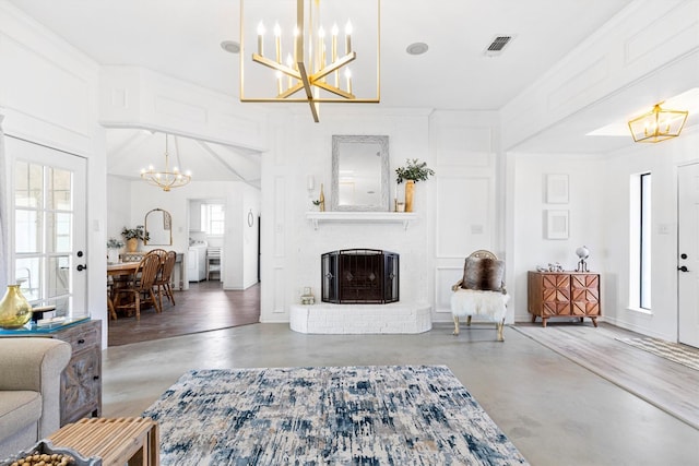 living room with ornamental molding, a brick fireplace, and a chandelier