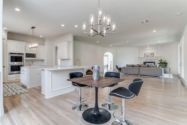 dining room featuring crown molding, sink, a notable chandelier, and light hardwood / wood-style floors