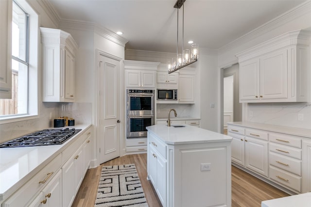 kitchen featuring appliances with stainless steel finishes, a kitchen island with sink, sink, and white cabinets