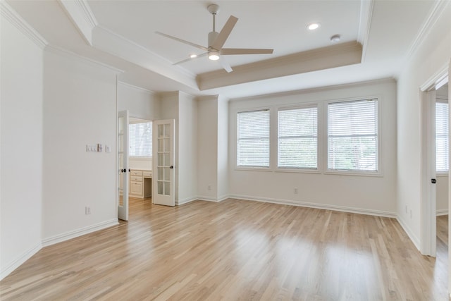 spare room featuring crown molding, a tray ceiling, ceiling fan, and light wood-type flooring