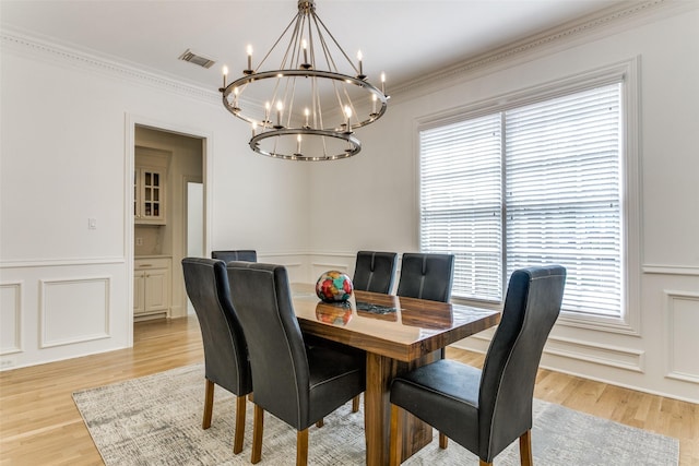 dining space with a notable chandelier, light hardwood / wood-style flooring, and ornamental molding