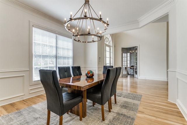 dining area featuring crown molding, a healthy amount of sunlight, an inviting chandelier, and light hardwood / wood-style flooring